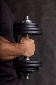 Close-up of a single-arm dumbbell for exercise held by a strong male hand 스톡 사진