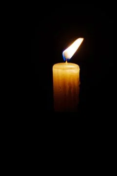 Close-up single candle burning on dark black background Stock Photos