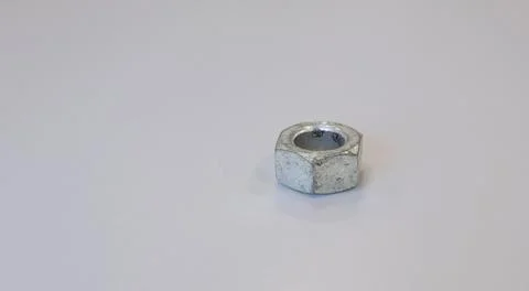 Close-up of a single metal hex nut placed on a clean light grey background Foto stock