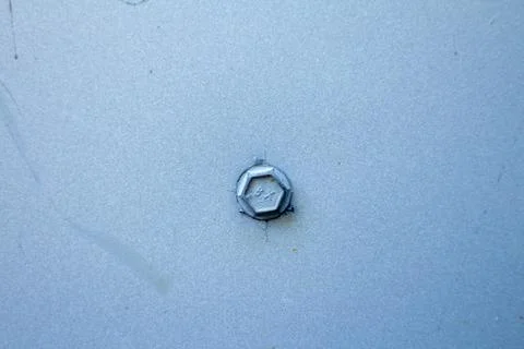 Close up of a single metallic hex head bolt fastened onto a light blue surface Fotos de archivo