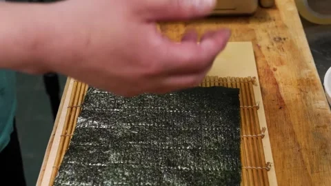 Close-up of a Single Nori Seaweed Sheet Placed on a Bamboo Sushi Rolling Mat (Ma Stock Footage 333496895