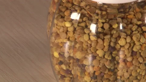 Close up of single rolling plastic jar of pollen with white cap on table Stock Footage 220651751