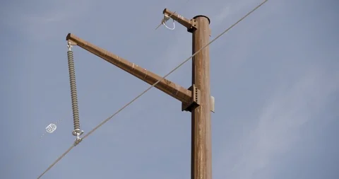 Close Up of Single Rusted Pole with Power Lines Against Blue Sky Stock Footage 89942577