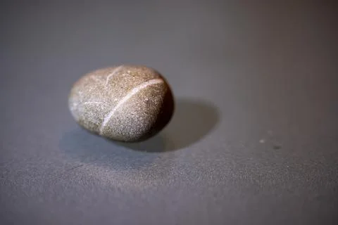 A close-up of a single smooth stone with a white stripe pattern Foto stock