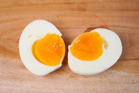 A close-up single soft-boiled chicken egg cut cleanly into two halves, plac.. Stock Photos