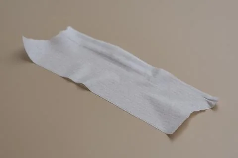 Close-up of a single strip of white adhesive paper tape isolated on a tan sur Stock Photos