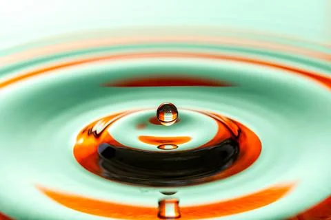 Close-up of a single water drop creating colorful concentric ripples Fotos Stock