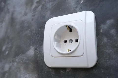 Close-up of a single white electrical power socket mounted on a dark raw po.. Stock Photos