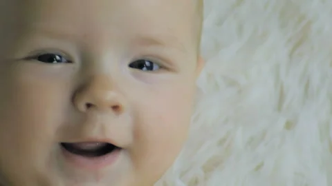 Close-up of a six-month boy lying on a white crib smiling and looking into the.. Stock Footage 99723804