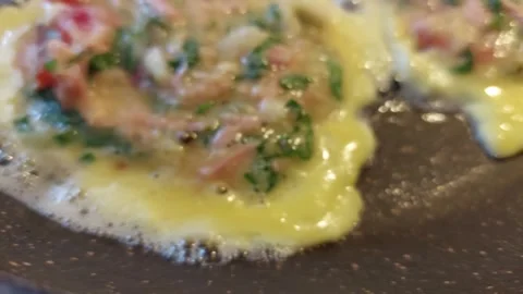 Close-up of Sizzling Egg Mixture with Herbs in a Pan Stock Footage 333642326