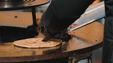 A close-up of a sizzling flatbread grill topped with a freshly baked flatbread Stock Footage 344873595