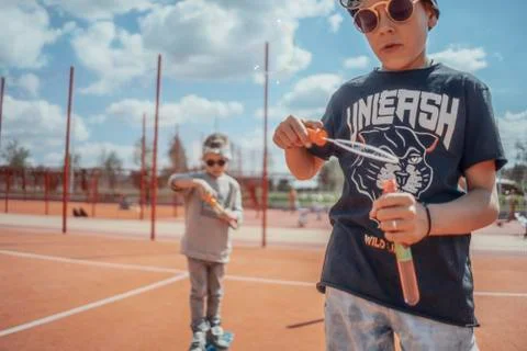 Close up of skateboading and making bubbles boys at colourful playground. Stock Photos