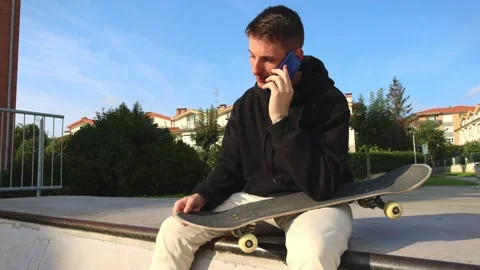 Close-Up of a Skater Sitting on the Half Pipe Edge Making a Call on His Sma.. Stock Footage 285765954