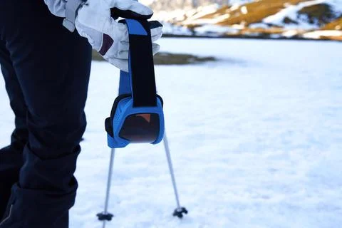 Close-up of ski goggles held by a hand equipped with a snow glove. Stock Photos