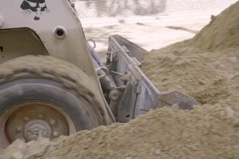 Close up of skid steer loader bucket pushing and dumping sand Stock Footage 345412382