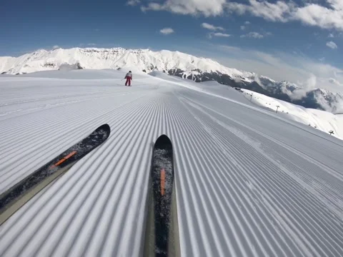 Close-up skiing glides down the undulating snowy slope to mountains on horizon Stock Footage 162782359