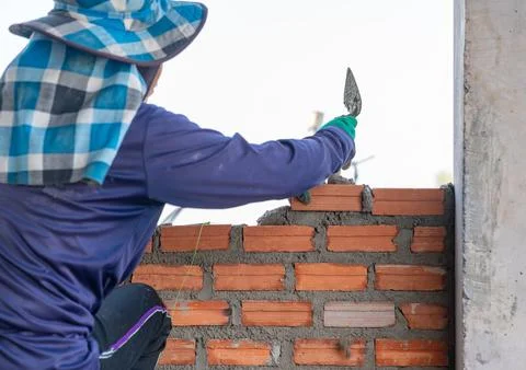 Close-up of a skilled bricklayer or mason working diligently on a new const.. Stock Photos