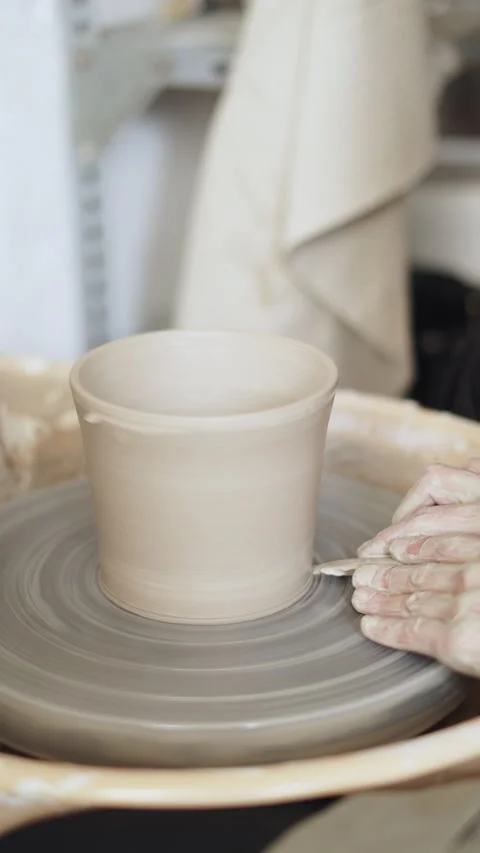 Close-up of skilled hands using a wooden rib to define the base of a clay v.. Stock Footage 272839793