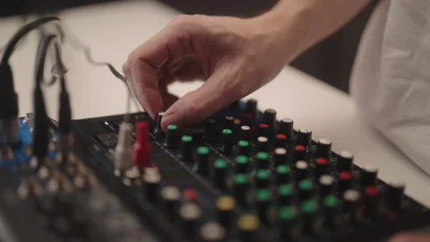 Close-up of skilled sound engineer adjusting faders and knobs on audio mixing 스톡 동영상 324867608