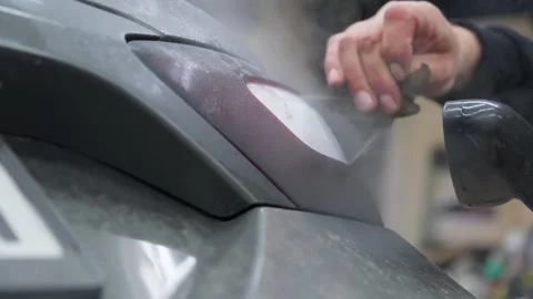 Close-up of skilled worker removing old tint film from a car tail light using 스톡 동영상 337537916