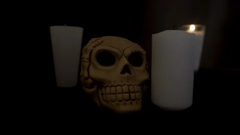 Close up on a skull with a candle light off on the back Stock Footage 96470578