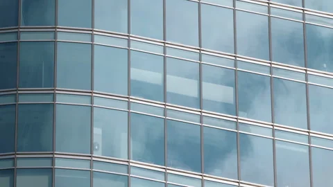 Close up skyscraper glass facade reflecting moving clouds, blue sky mirrored Video stock 333651561