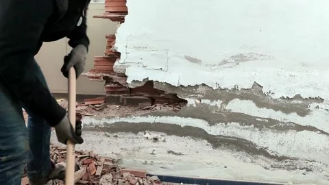 Close-up of a sledgehammer smashing a white plaster wall, red bricks breaking an Stock-Footage 328402121