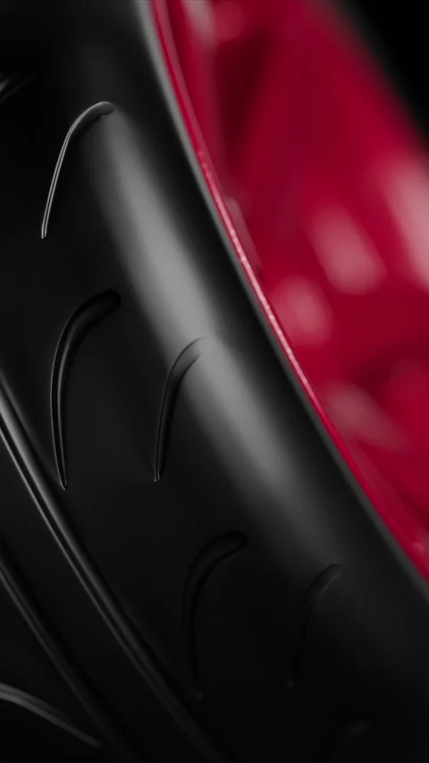 Close-up of a sleek black tire tread with a vibrant red rim in the background Stock Footage 325791256