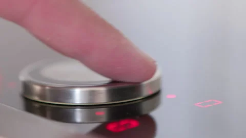 A close-up of a sleek metallic control button on a smooth surface reflecting sof Stock Footage 281596475