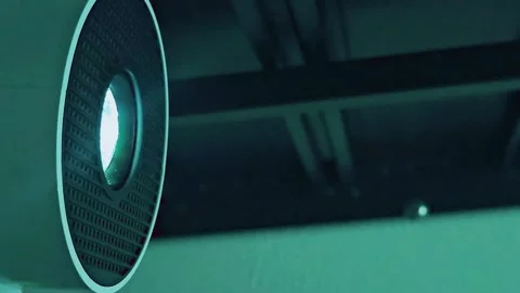 Close-up of a sleek modern mini projector lens glowing with bright cyan light Stock-Footage 345768046