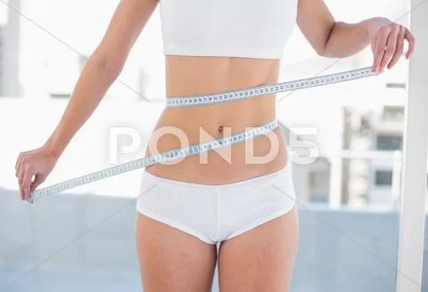 Close up of a slender woman measuring her waist Stock Photos