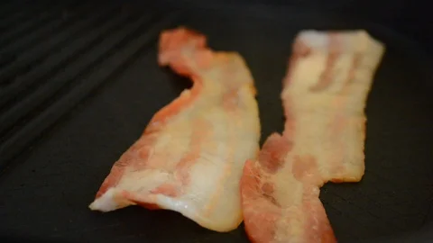 Close-up of a slice of bacon fried on a hot grill. Video stock 88868746