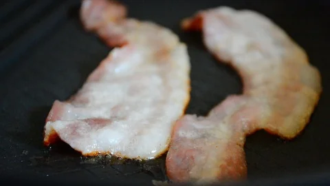 Close-up of a slice of bacon fried on a hot grill. Video stock 88868777