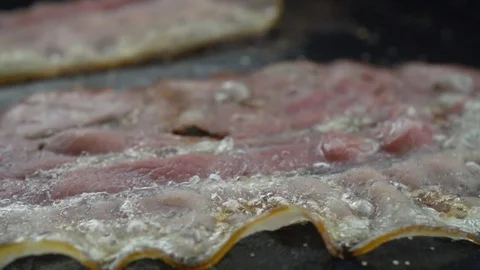Close-up of a slice of bacon fried on a hot grill 스톡 동영상 104972795