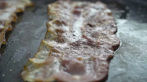 Close-up of a slice of bacon fried on a hot grill Video stock 104972814