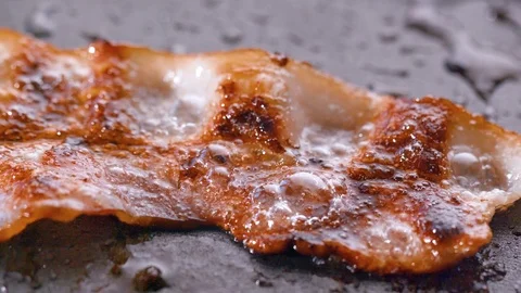 Close-up of a slice of bacon fried on a hot grill Video stock 104974733