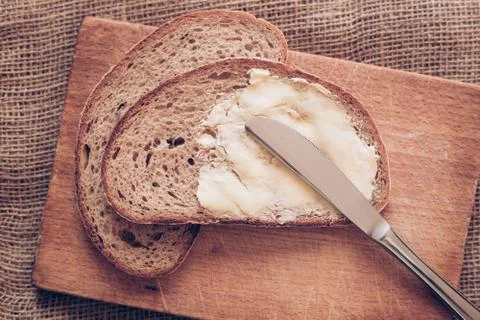 Close-up slice of bread with butter and knife on the wooden desk, poverty Stock Photos