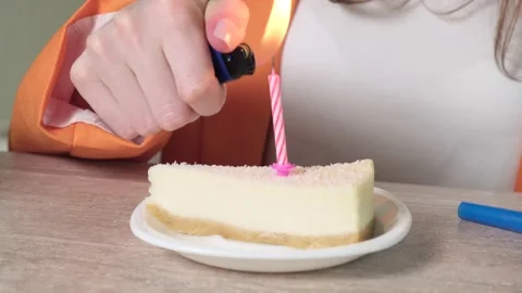 Close-up of a slice of cake with a candle. Lights a candle and blows. 4k video. Video stock 138041370
