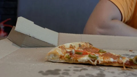 Close up the slice of pizza lies in a pizza box in the background of a person Видео 111383394