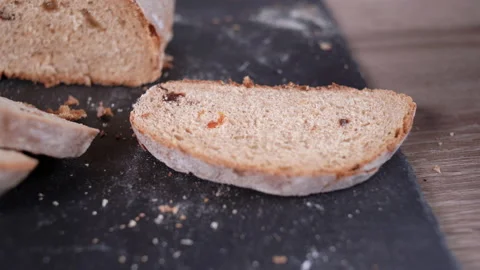 Close-up of a slice of rye bread with raisins, a man s hand smears a spread Stock Footage 150294693