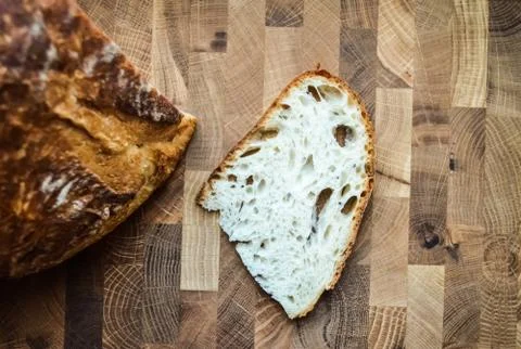 Close-up slice of white fresh bread near a wheat bun on a wooden table. Stock Photos