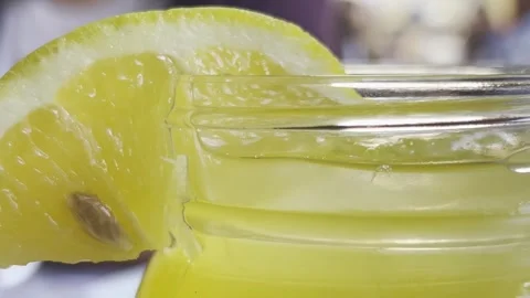 Close-up of a slice of yellow lemon on the rim of a glass jar filled with Video stock 297069187