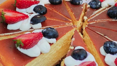 Close-up of sliced baked cheesecake topped with fresh berries and cream. Stock Footage 339780758