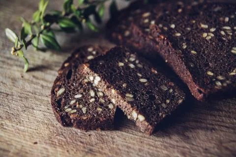 Close-up of the sliced brown bread at the cutting board on the wooden table w Stock Photos