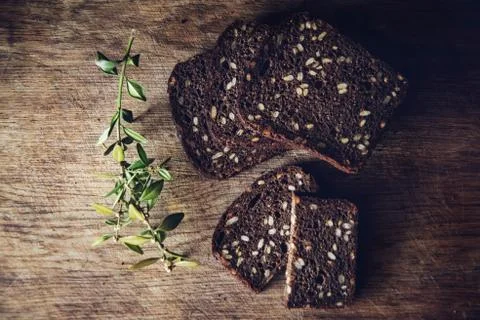 Close-up of the sliced brown bread at the cutting board on the wooden table w Stock Photos