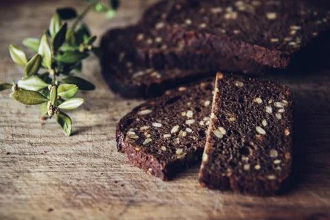 Close-up of the sliced brown bread at the cutting board on the wooden table w Stock Photos