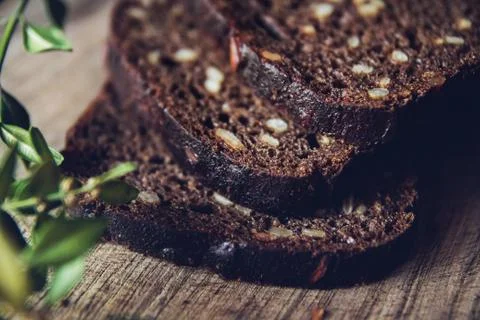 Close-up of the sliced brown bread at the cutting board on the wooden table w Stock Photos