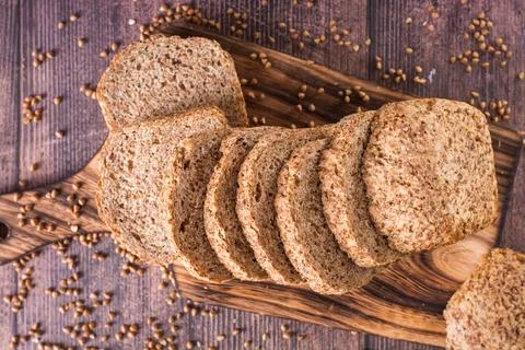 Close up of sliced buckwheat bread on a cutting board and cereals on the ta.. Stock Photos