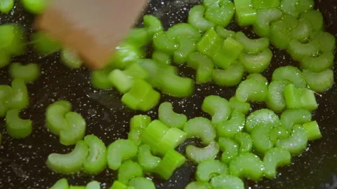 Close-up of sliced celery stalks in a frying pan, in hot olive oil. Video 100fps Stock Footage 309301795