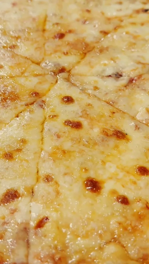 Close-up of sliced cheese pizza with melted golden mozzarella, tomato sauce and Stock Footage 337231908